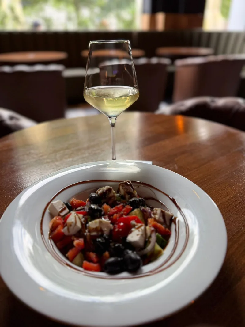 Kieliszek białego wina podany ze świeżą sałatką w Fajka Bar Lounge